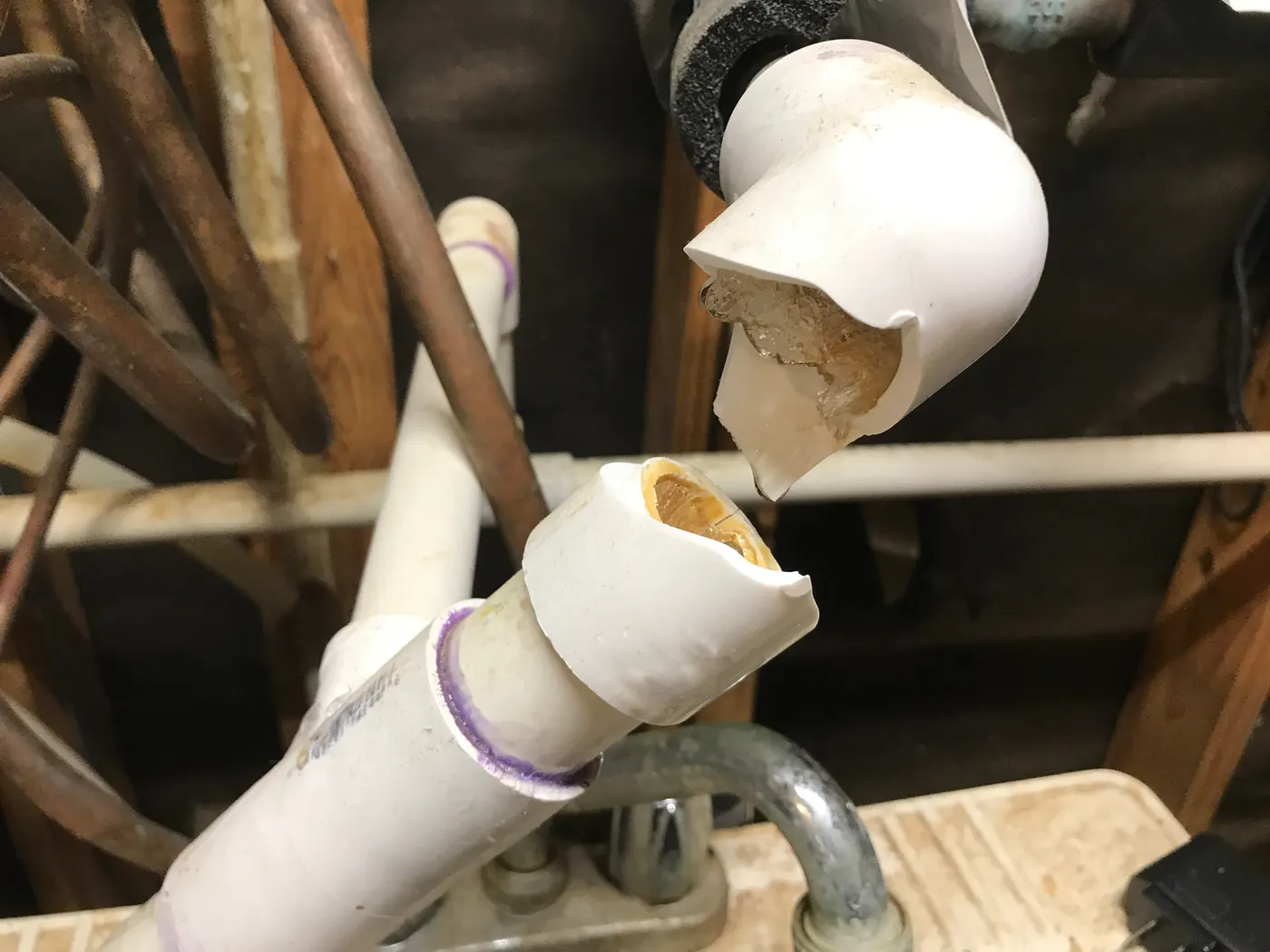 A PVC water pipe split open by ice after freezing in an unheated utility space