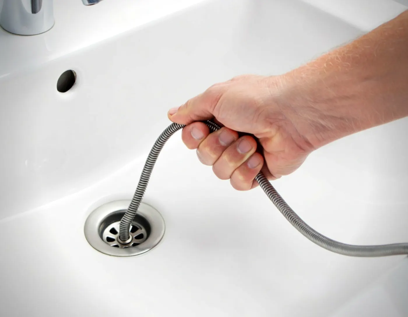 Clearing a clogged bathroom sink drain with a plumbing snake