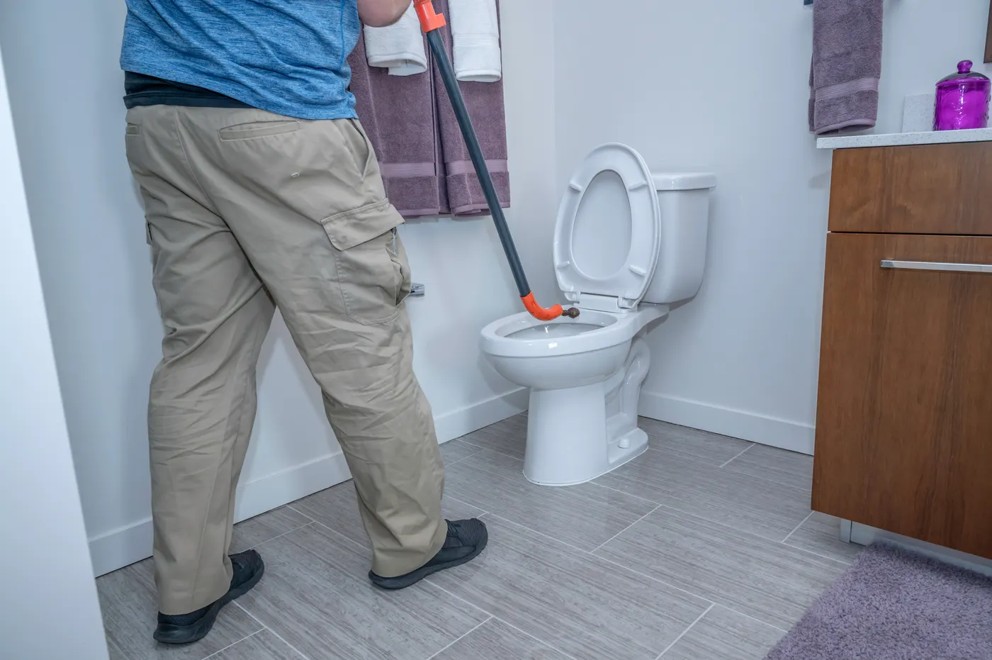 Plumber clearing a clogged toilet with a closet auger